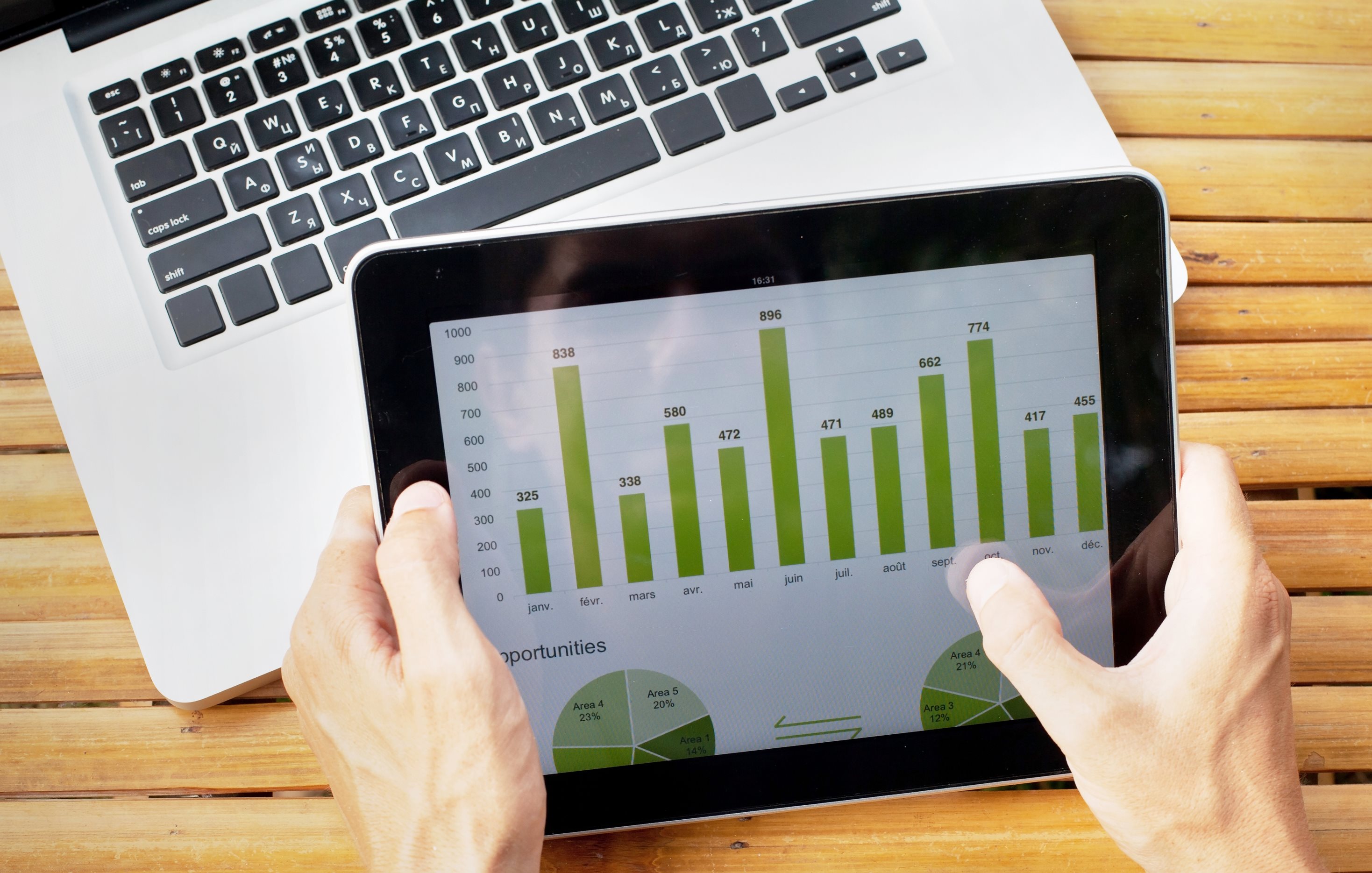 iPad mit Grafik und Laptop im Hintergrund