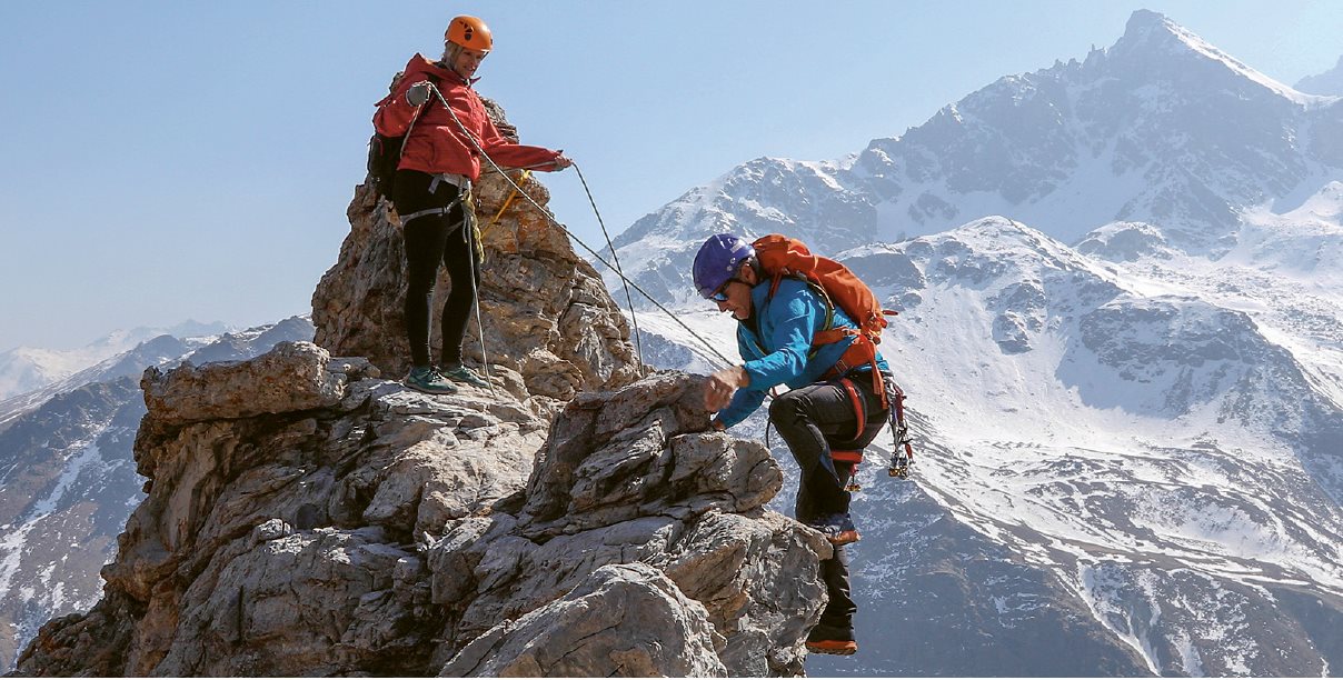 Zwei Bergsteiger mit Kletterausrüstung erklimmen den Gipfel eines Berges