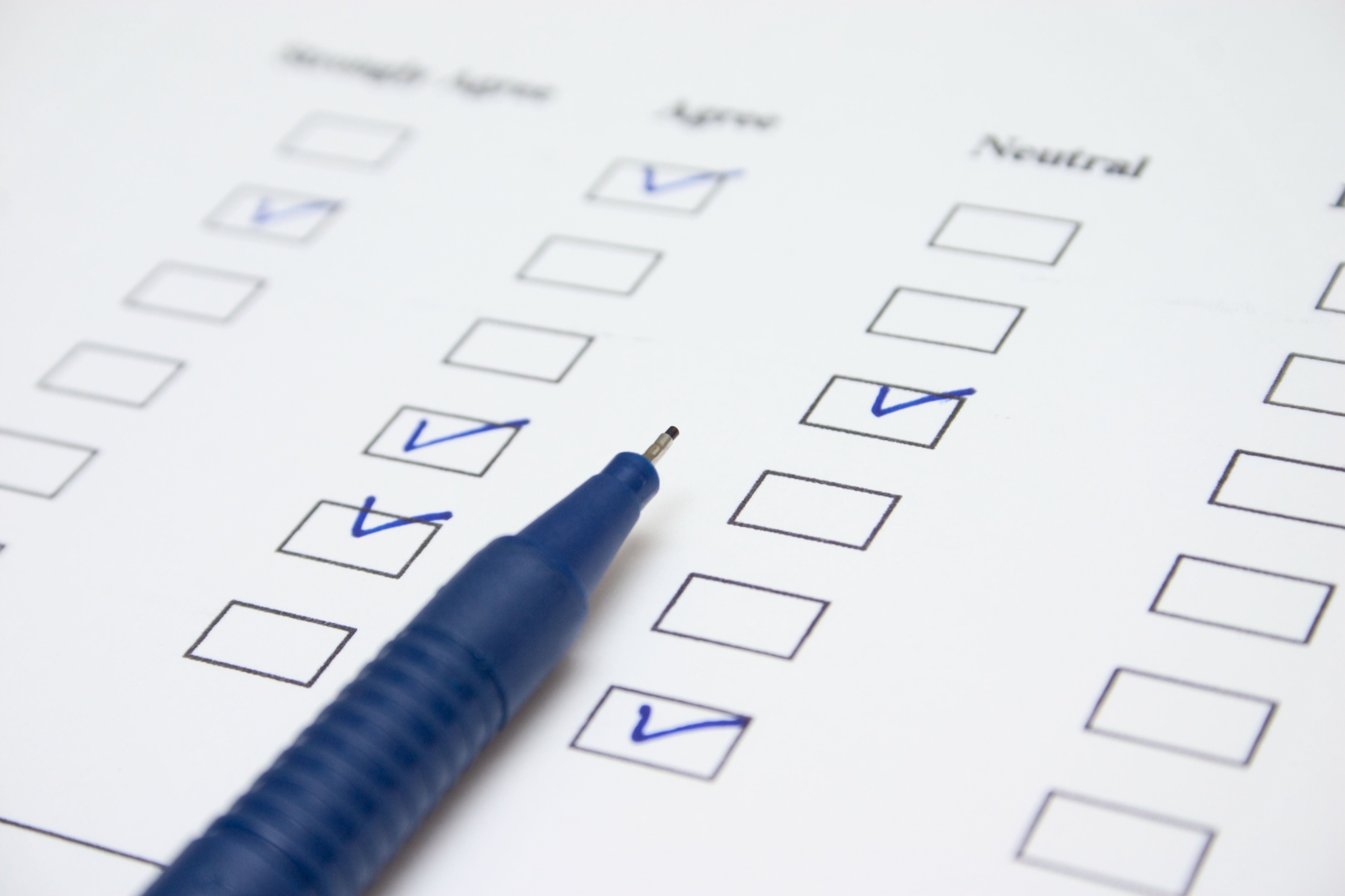 Ein blauer Stift und darunter liegt ein Blatt mit Checkboxen
