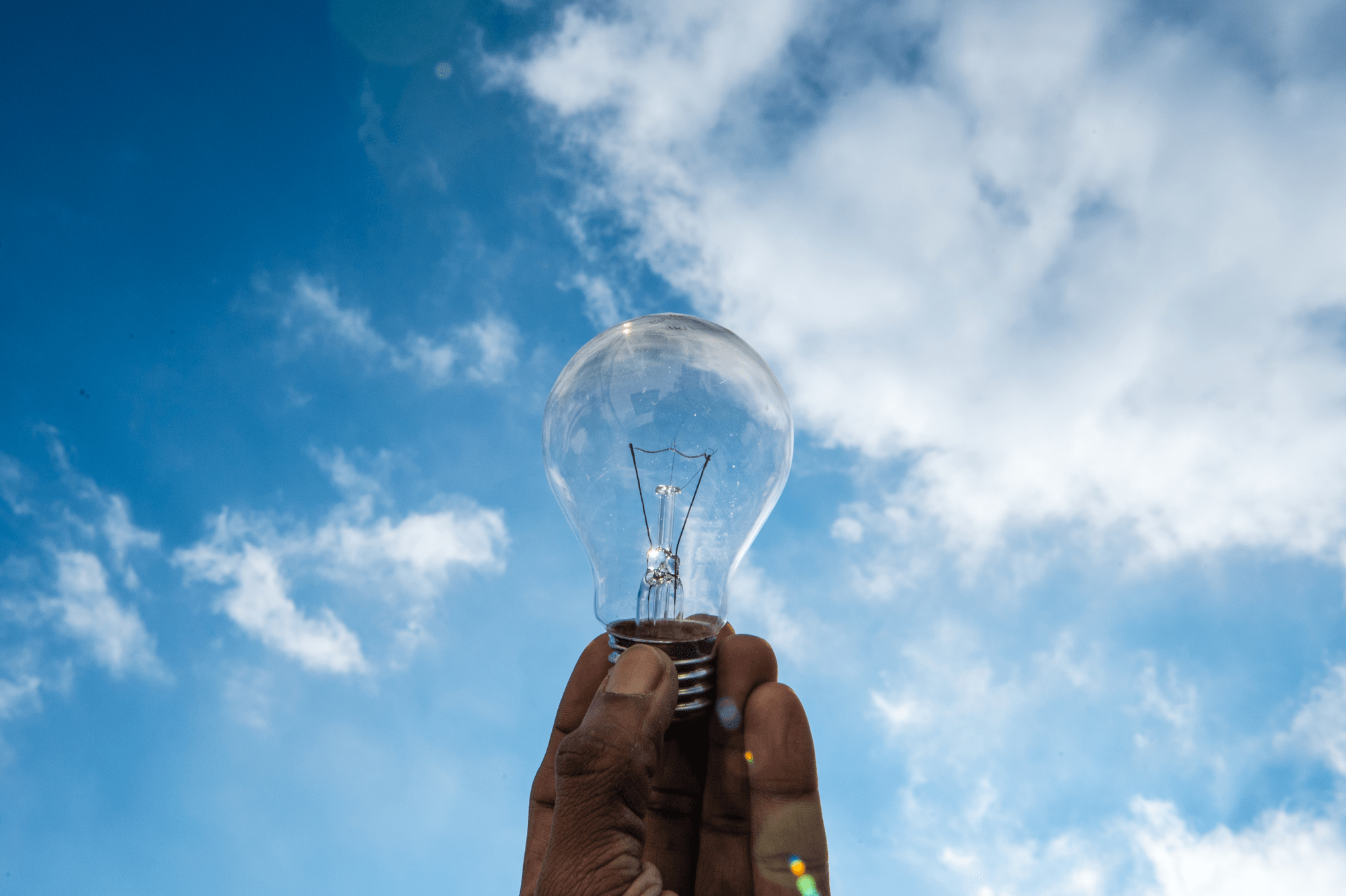 Eine Hand hält eine Glühbirne in die Luft