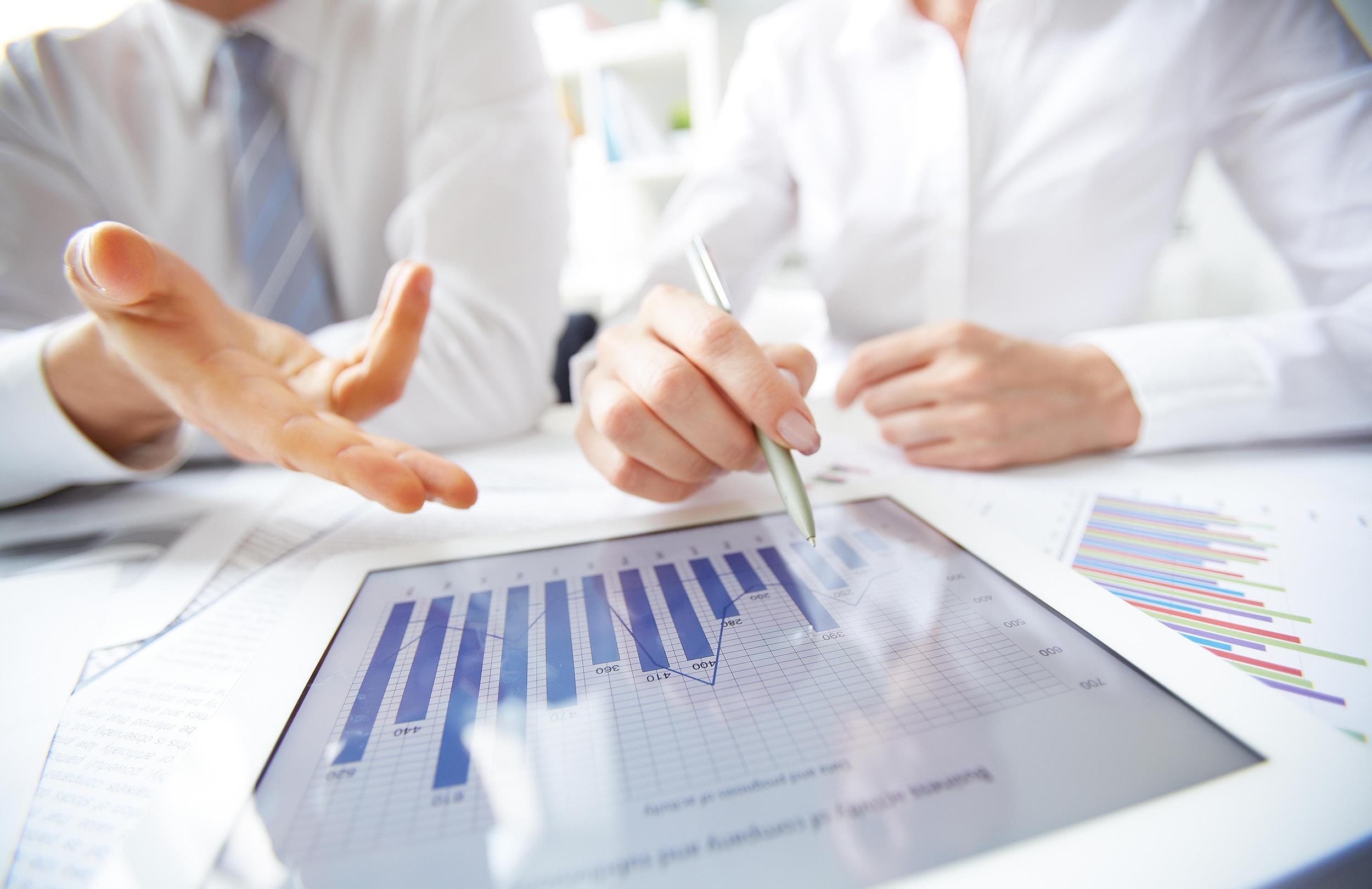 Un iPad affiche un graphique et des mains de deux personnes